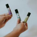 person holding up three vials of essential oils - thought to treat spider veins at home.