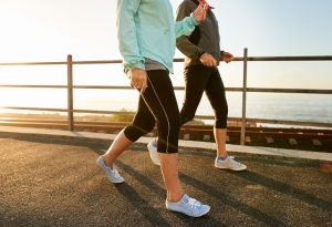 two people waking by a beach. Walking is great for spider vein treatment recover